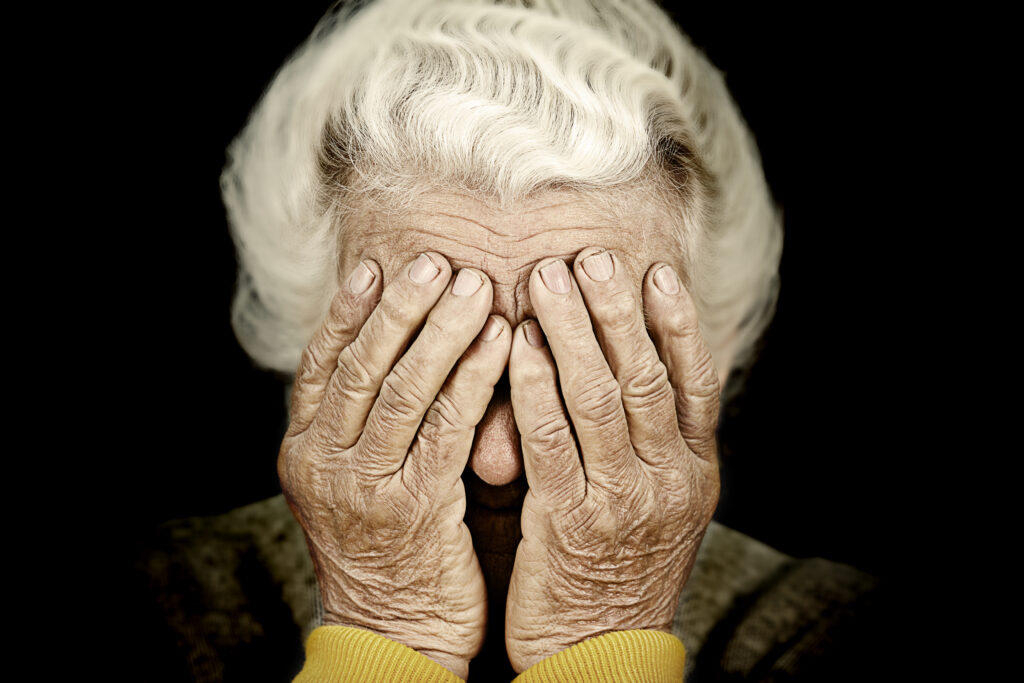 personne âgée se tenant la tête dans ses mains